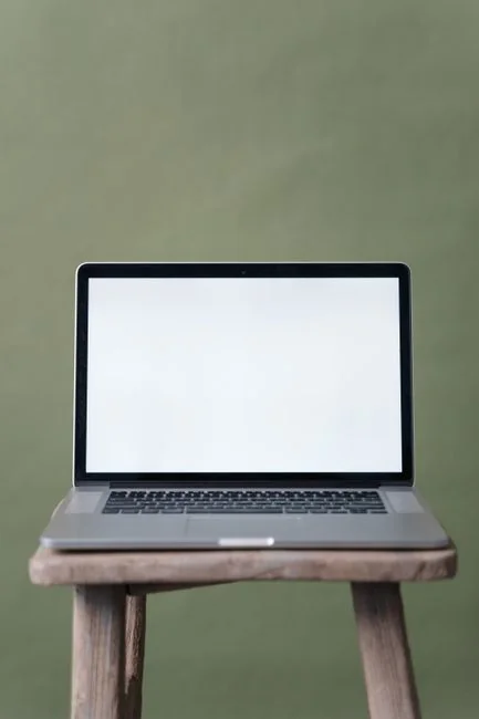 Open laptop showing a website screen on a wooden table in an outdoor terrace setting.