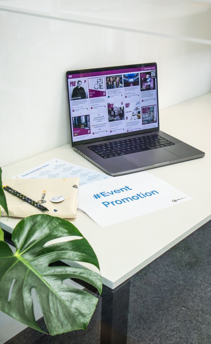 Clean office space with a laptop displaying social media, papers, and a plant for event promotion.
